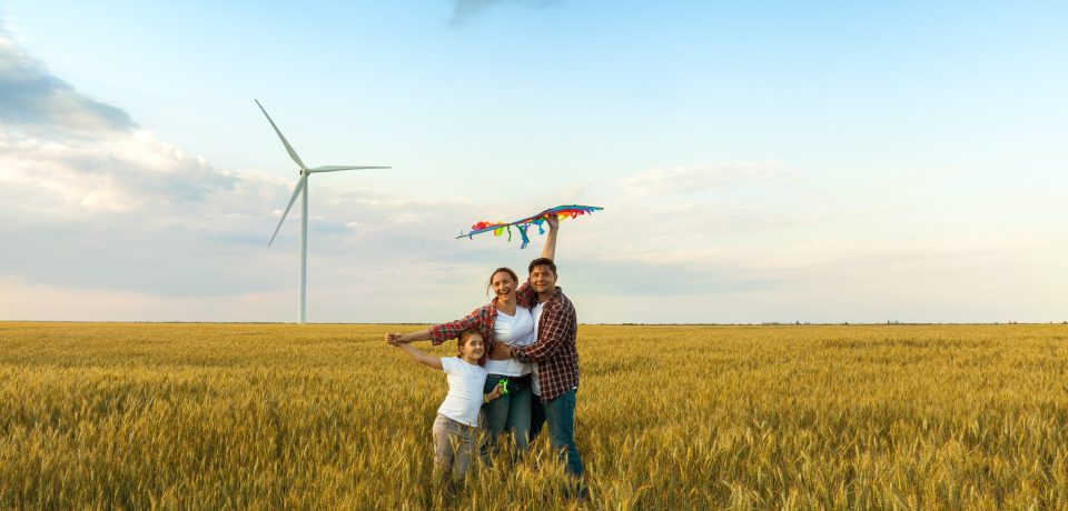 Happy family having fun with kite on the field. Beautiful family with flying colorful kite over clear sky. Free, freedom concept.