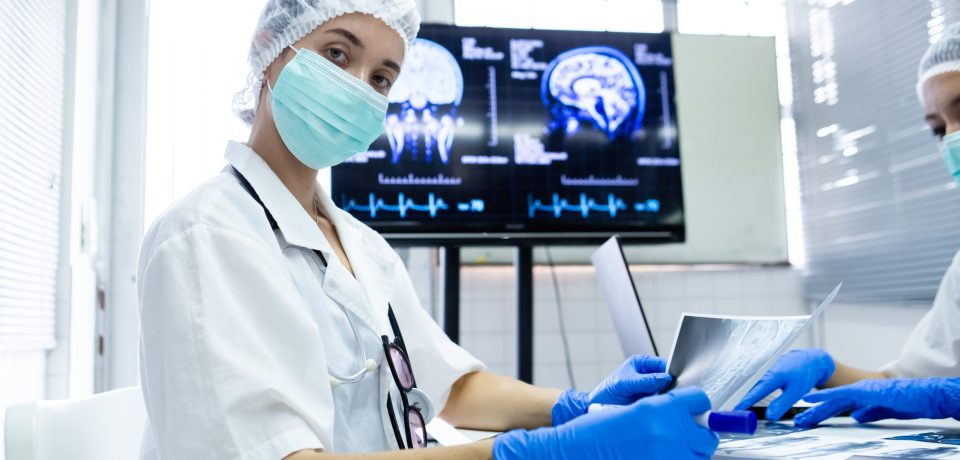 young female medical were mask and blue glove holding x-ray film. Learn about brain surgery. medical students studying  brain disease diagnosis through learning from X-ray film.