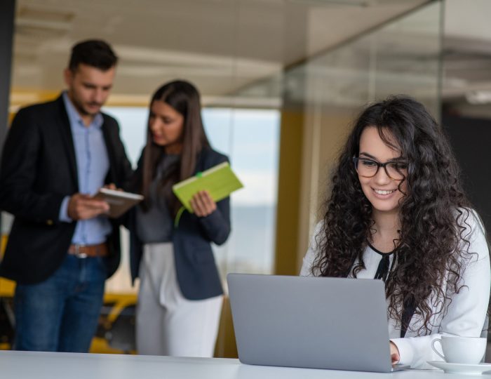 Confident attractive young business woman with tablet in hands in modern office start up office Confident attractive young business woman with tablet in hands in modern office start up office in front of working business team